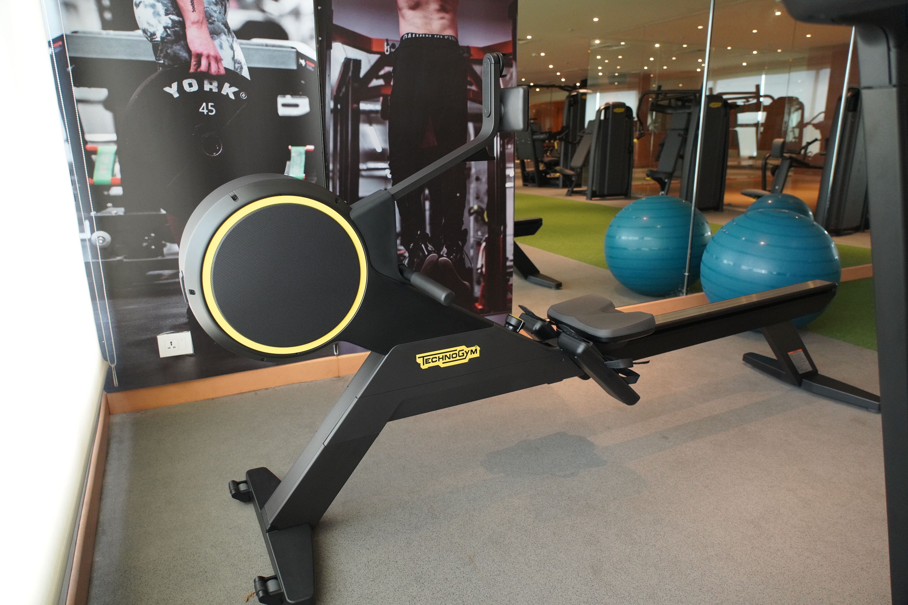 A gym with a treadmill, weight machine, and exercise balls.