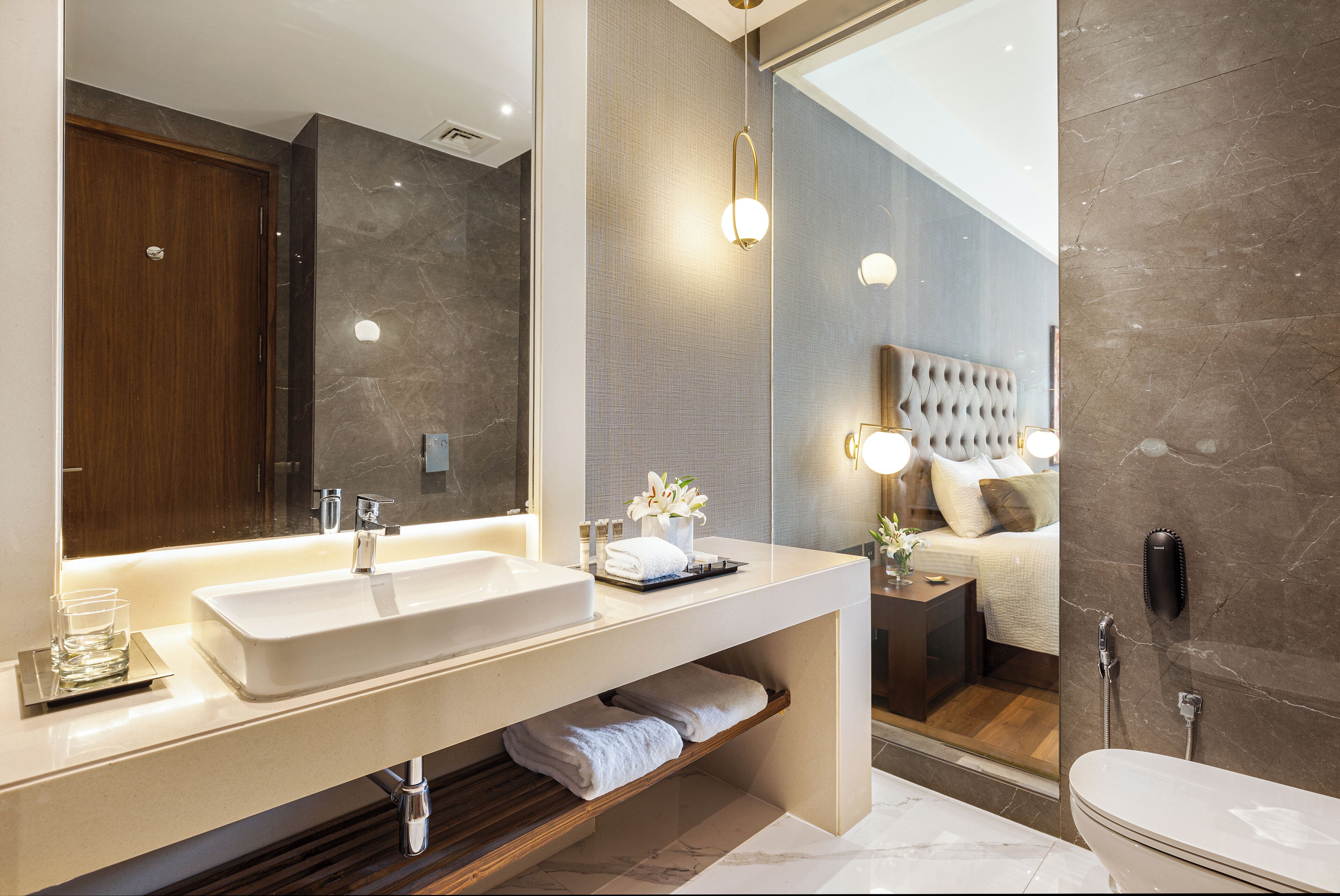 Un bagno moderno con un grande specchio, due lavabi, un mobile contenitore con portasci asciugamani e una cabina doccia separata.