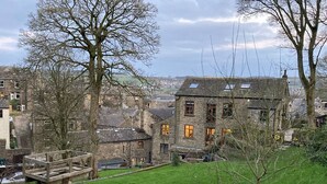 A stone building with multiple windows and a wooden deck. - OldMill-2Bed-Sleeps6-PrivateGarden-OptionalHotTub (Keighley)