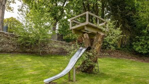 A playground with a slide and a treehouse structure. - OldMill-2Bed-Sleeps6-PrivateGarden-OptionalHotTub (Keighley)