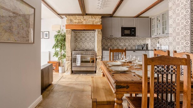 A kitchen with a stone wall, wooden beams, and patterned tiles. - OldMill-2Bed-Sleeps6-PrivateGarden-OptionalHotTub (Keighley)