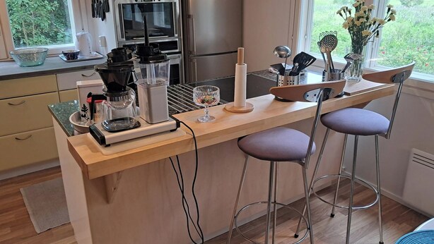 A modern kitchen with a bar area, stainless steel appliances, and a view of the garden.