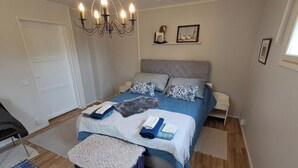 A neatly arranged bedroom with a bed, bedside tables, a chandelier, and a window.