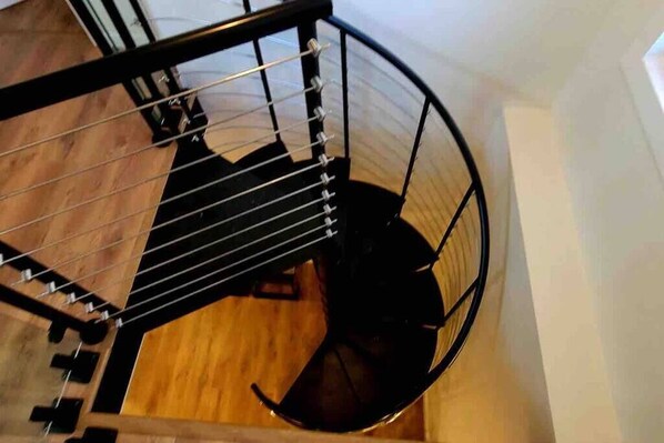 Una escalera de caracol con suelo de madera y barandillas de metal negro.