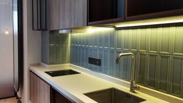 Cozinha moderna com duas pias, torneira de aço inoxidável e iluminação atrás do fogão.