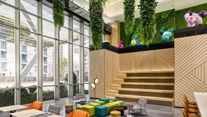 A modern indoor space with large windows, green hanging plants, colorful seating, and a wooden wall with geometric patterns. - Artyzen Habitat Qiantan Shanghai   (Shanghai)