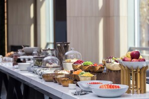 A buffet table with various food items and utensils.