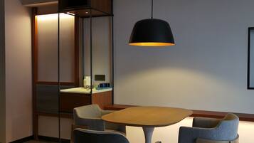 A modern dining area with a round table, two chairs, and a pendant light.
