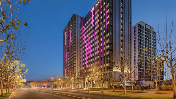 Un hotel moderno de gran altura, con fachada contemporánea y señalización iluminada.