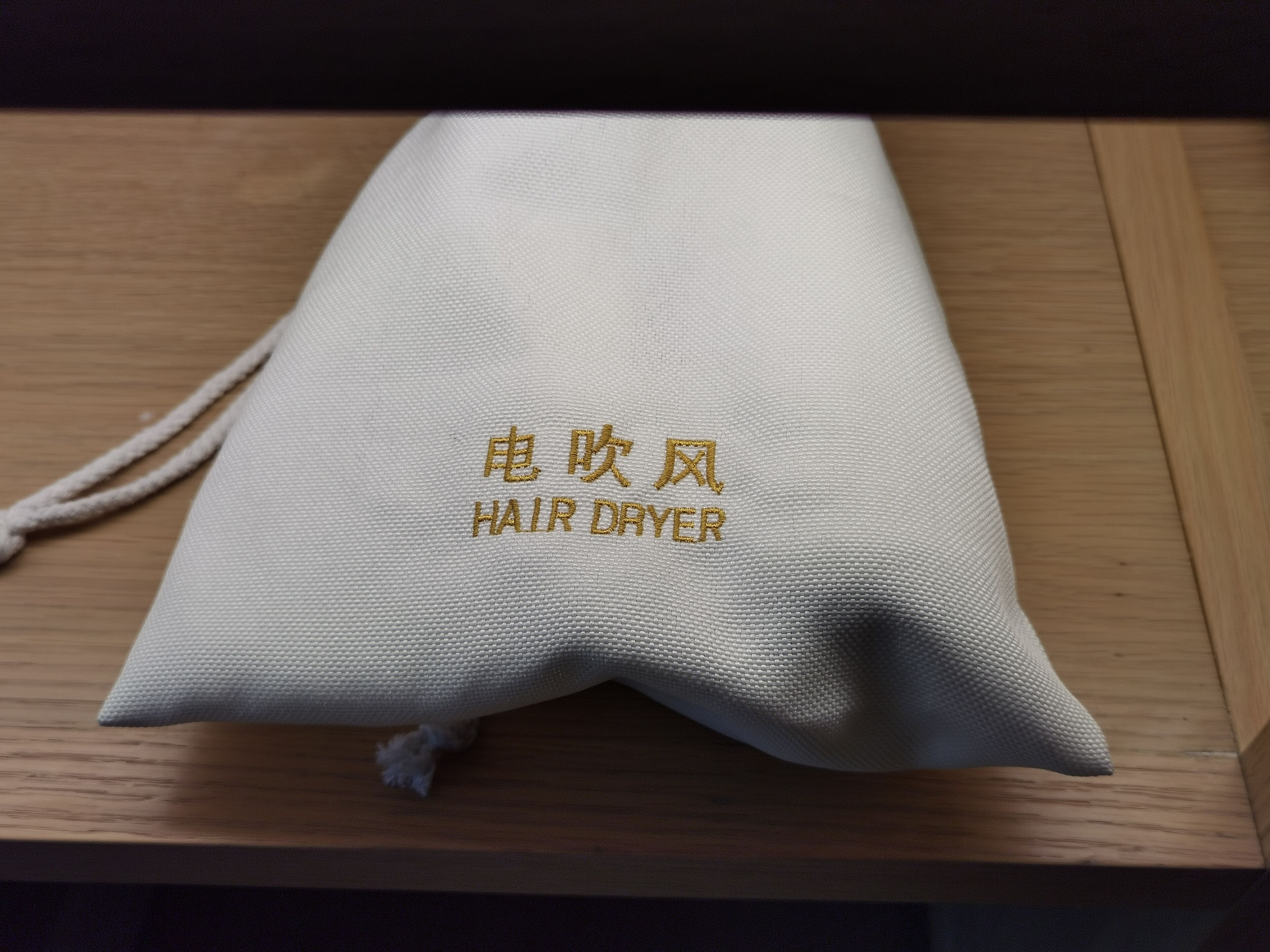 A white fabric item with embroidered text that reads "HAIR DRYER" and some non-English characters.