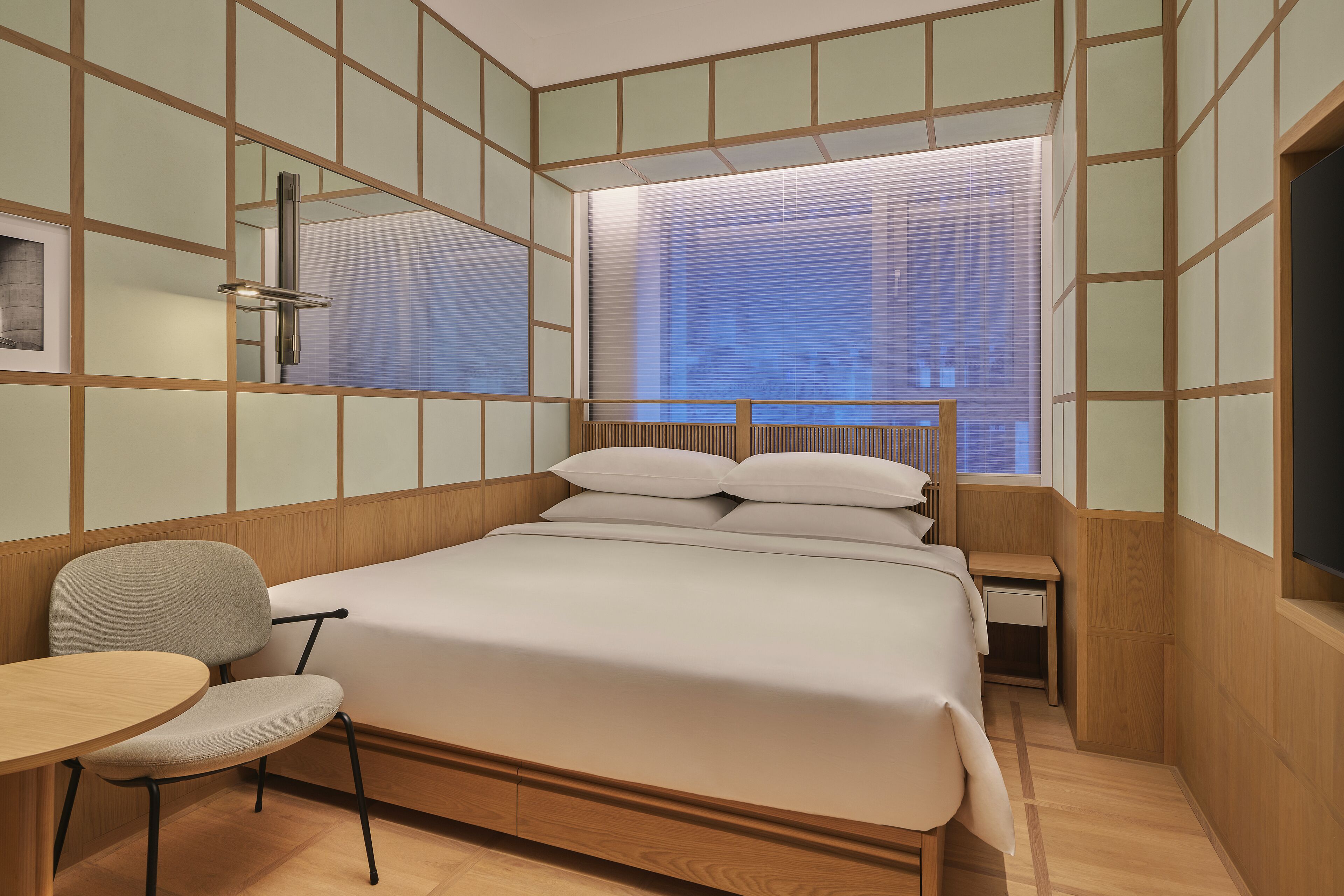 Un dormitorio con una cama de madera, una mesita pequeña y una silla.