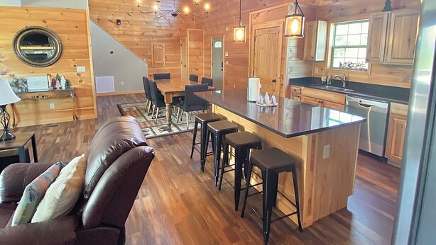 A spacious wooden interior with a dining area, kitchen, and a cozy seating area with a leather couch. - Modern cabin with mountain views, just minutes from local attractions (Gatlinburg)