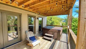 A wooden deck with a hot tub, a chair, and a table. - Modern cabin with mountain views, just minutes from local attractions (Gatlinburg)