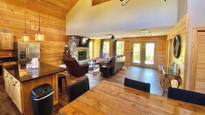 A spacious living area with a wooden ceiling, a stone fireplace, and a large TV. - Modern cabin with mountain views, just minutes from local attractions (Gatlinburg)