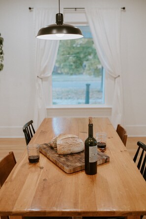Una mesa de madera con un pan, una botella de vino y una copa de vino sobre una tabla de cortar.