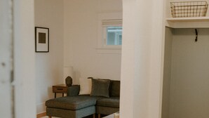 Un salon avec un canapé d’angle, une petite table et un panier posé sur une étagère.