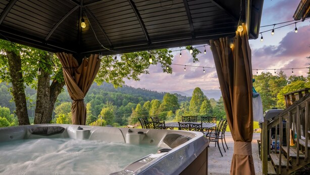 Un jacuzzi bajo una zona cubierta con vista a un paisaje boscoso.