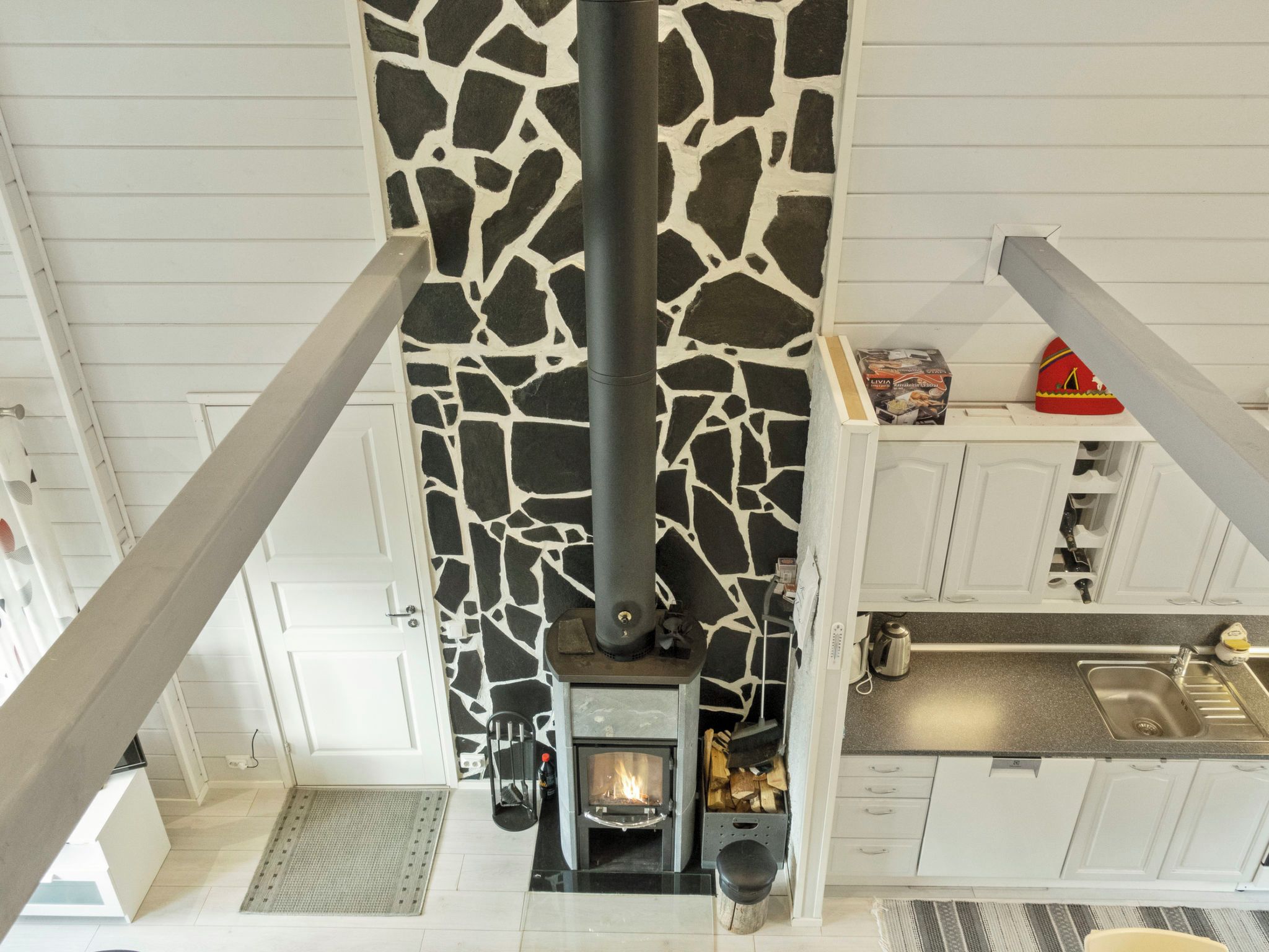 A modern kitchen with a stone-patterned wall, a built-in wood stove, and white cabinetry.