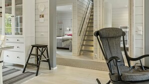 A modern interior with a staircase leading to a bedroom, a white cabinet, and a chair.