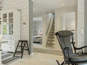 A room with a bed, a chair, a desk, and a staircase leading to another room.