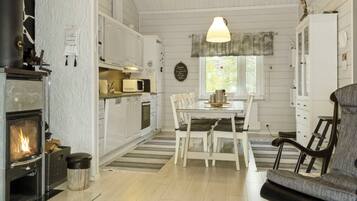 A cozy kitchen with a wood-burning stove, white cabinets, and a dining area with a table and chairs.