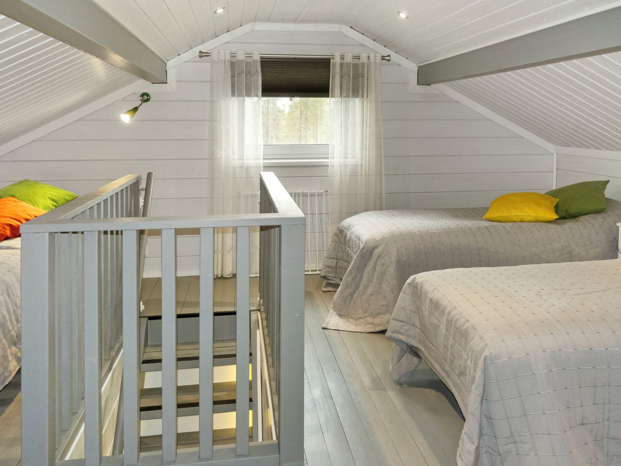 A bedroom with two beds, a window with sheer curtains, a small staircase, and a radiator.