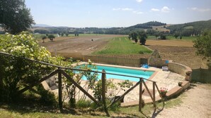Ein Poolbereich mit Blick auf landwirtschaftliche Felder und Hügel im Hintergrund.