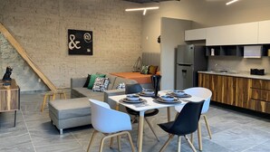 Een moderne keuken met een inbouwkoelkast, een eethoek met een tafel voor vier personen en een trap naar een hoger gelegen verdieping.