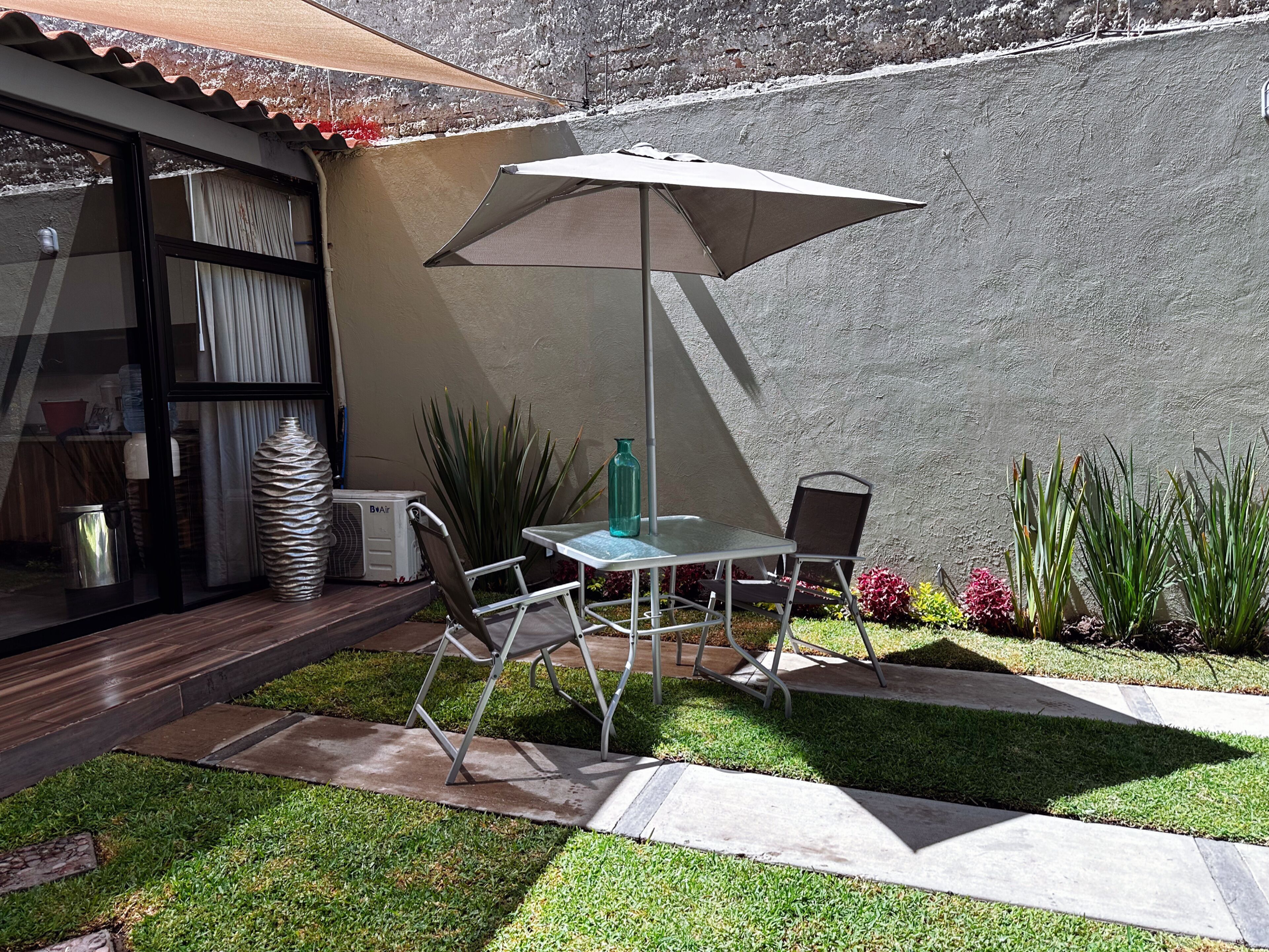 A patio with a table and chairs, a water bottle, and a fan.