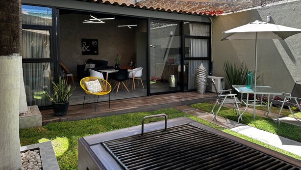 Een modern buitenterras met een eethoek, een barbecue en een zithoek.