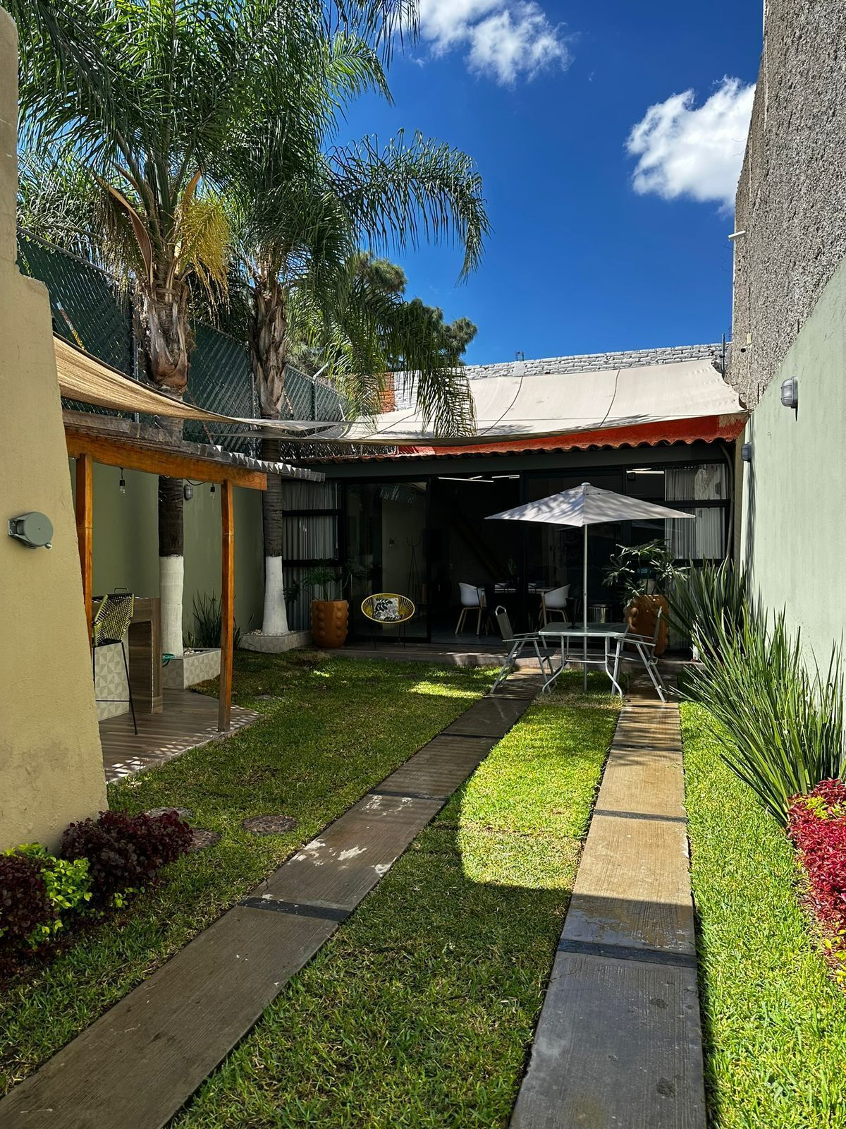 A courtyard with a covered seating area, a pathway, and a small garden with plants and a decorative pot.