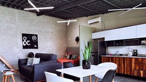 Een moderne woonruimte met een eethoek, een bank, een salontafel en een keuken met houten kastjes en een koelkast.