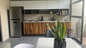 Een moderne keuken met een inbouwkoelkast, houten kastjes, een spoelbak en een koffiezetapparaat.