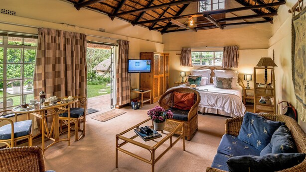 Amplia habitación con cama, televisión, zona de comedor y espacio de estar con una mesa de centro y sillas.