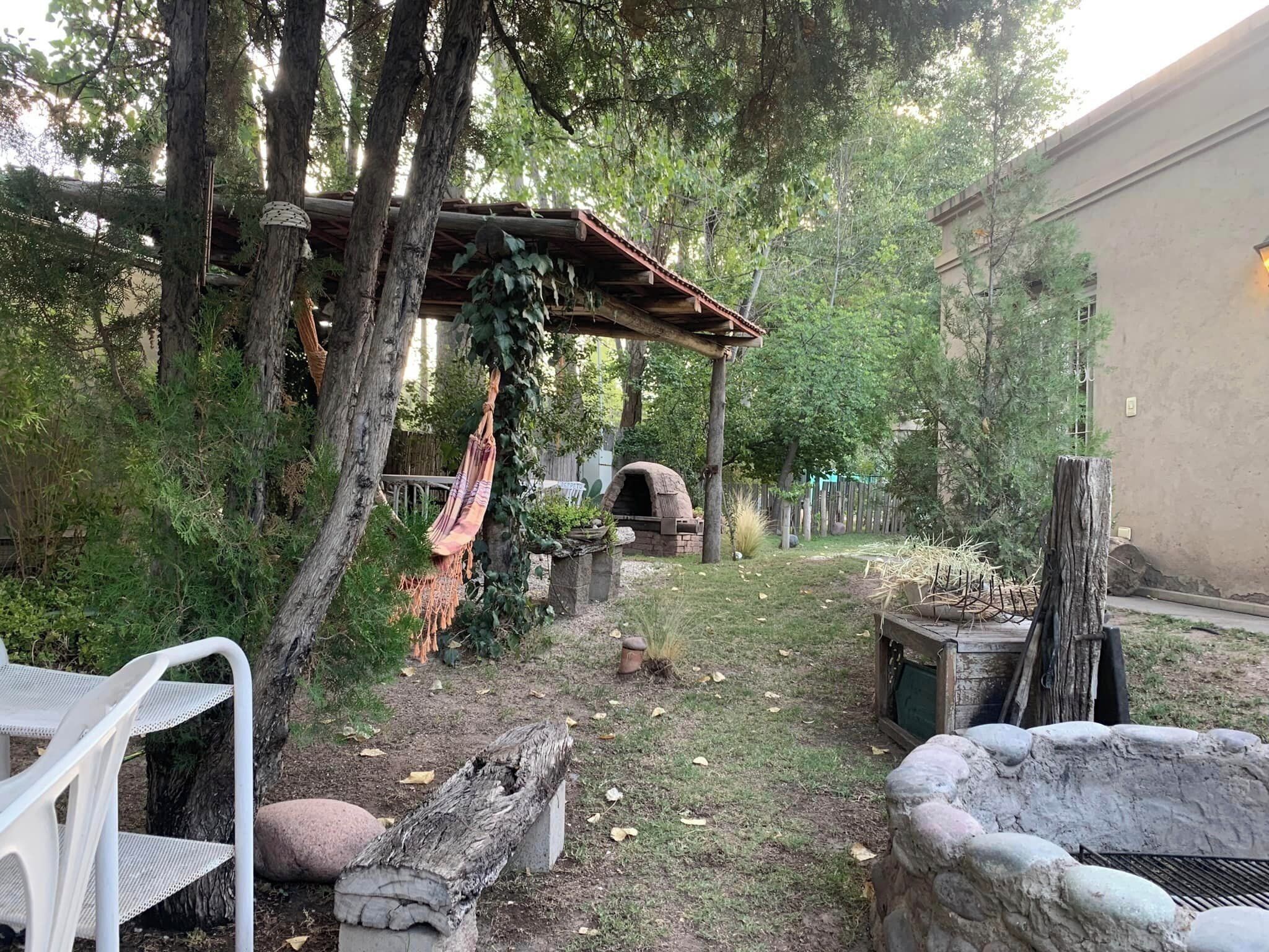 A backyard with a hammock, a brick oven, and a stone fire pit.