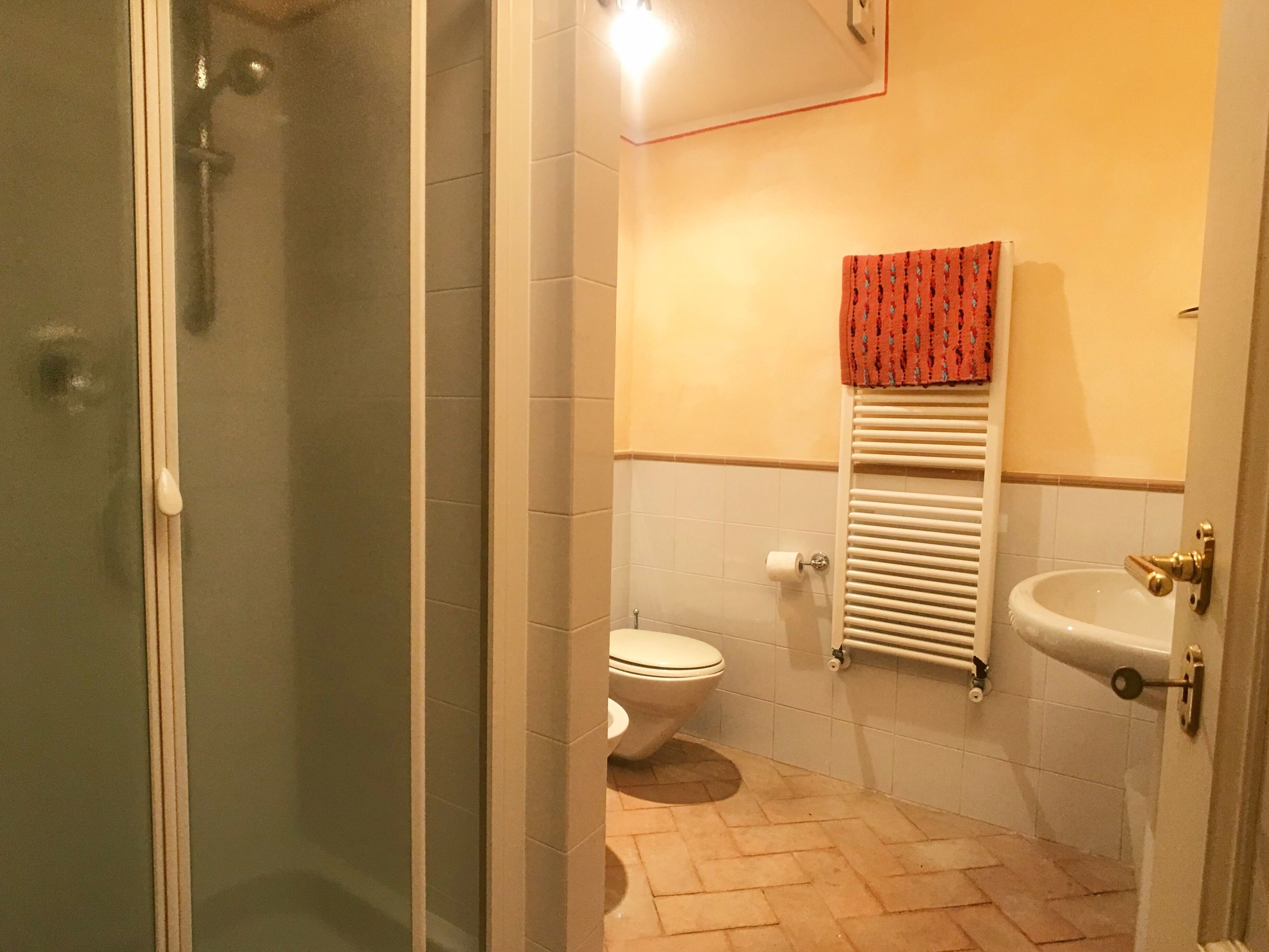 Une salle de bain comprenant des toilettes, un lavabo, une douche en verre et un porte-serviettes.