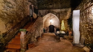 Une cour pavée de pierres, avec un escalier, une table entourée de chaises et un sapin de Noël.