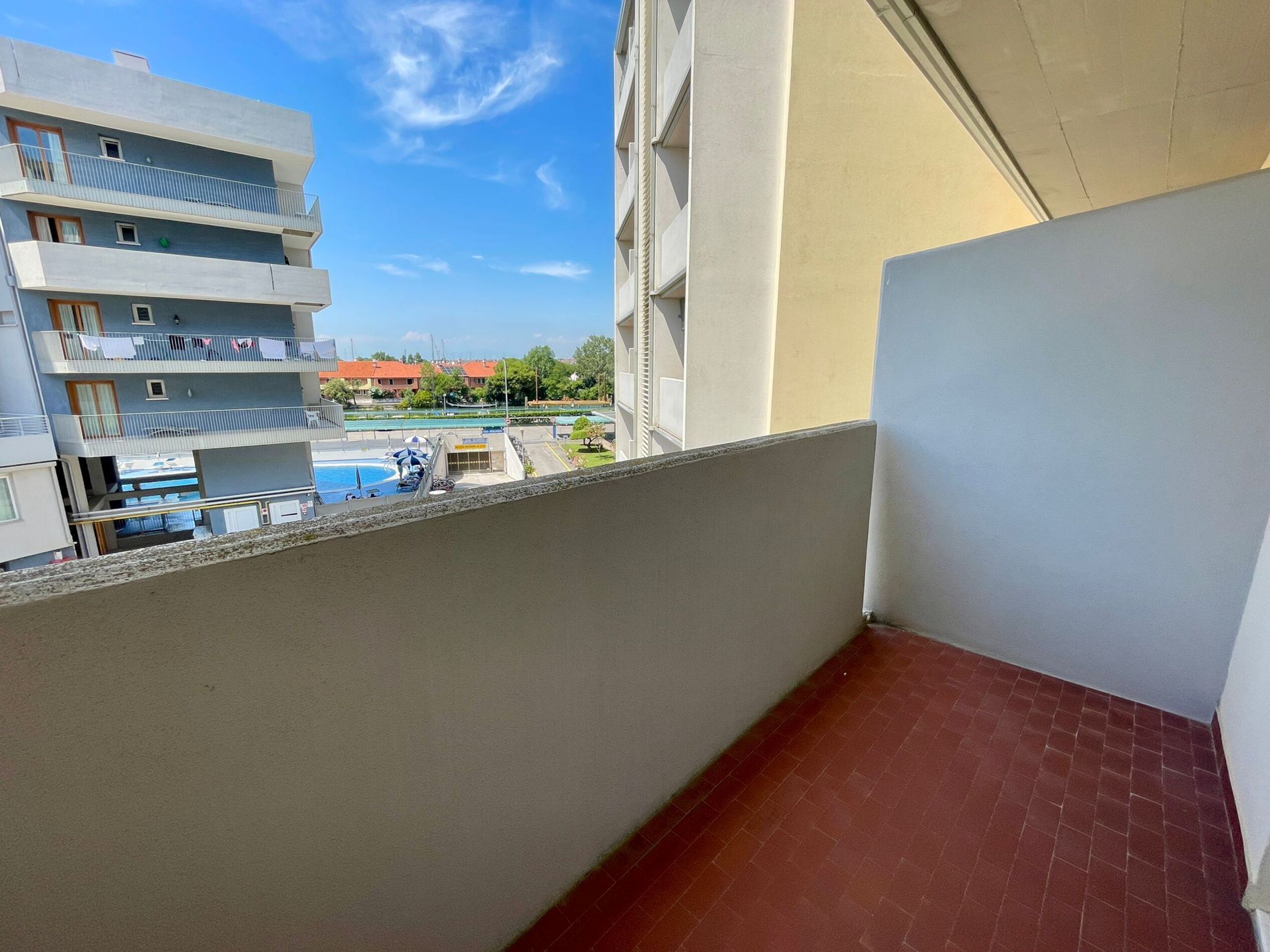 Un balcon donnant sur une piscine et les bâtiments adjacents.