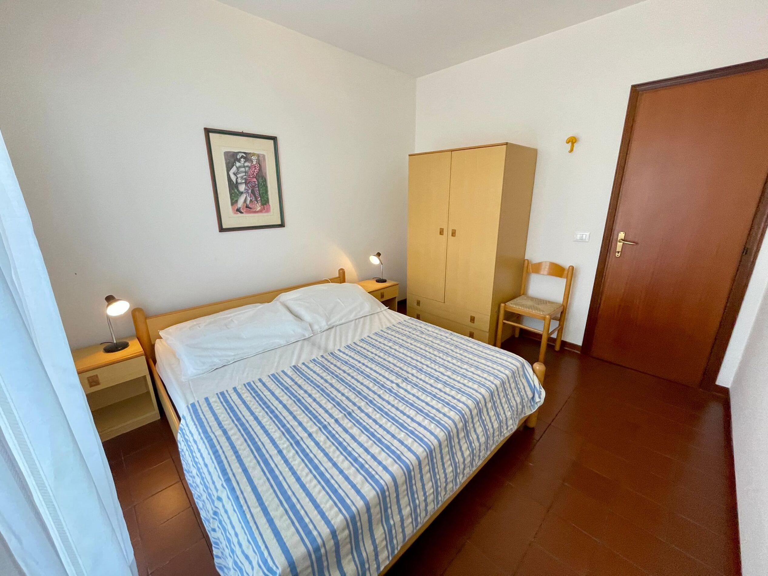 Une chambre à coucher avec un lit, une armoire, une chaise et une porte.