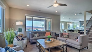 A spacious living room with a gray sofa, a wooden coffee table, and a large window offering a view of the outdoors.