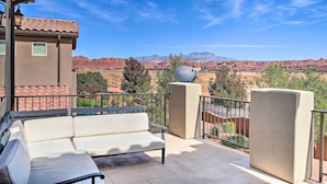 A balcony with a white sofa, a satellite dish, and a view of red rock formations.