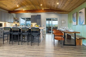 A modern kitchen with a wooden ceiling, bar stools, and a dining table set for six. - Lake Views - Game Room/Movie Room - Seattle (Seattle)
