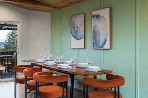 A dining area with a long table set for six, surrounded by six orange chairs. Two large abstract paintings are on the wall above the table. - Lake Views - Game Room/Movie Room - Seattle (Seattle)