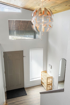 A room with a wooden ceiling, a white door, a window with blinds, a bench, a mirror, and a ceiling light fixture. - Lake Views - Game Room/Movie Room - Seattle (Seattle)