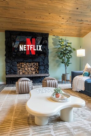 A living room with a stone fireplace, a white coffee table, and a couch. - Lake Views - Game Room/Movie Room - Seattle (Seattle)