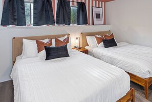 Two beds with white bedding and brown pillows, a bedside table with a lamp, and a window with curtains. - Lake Views - Game Room/Movie Room - Seattle (Seattle)