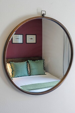 Una cama con almohadas verdes, un cabecero de madera y dos cuadros con imágenes de peces en la pared.