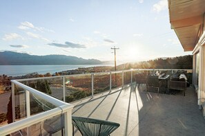 Ein Balkon mit Blick auf einen See und Berge, ausgestattet mit Stühlen und einem Tisch.