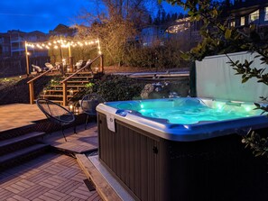 Ein Whirlpool mit Holzaußenverkleidung, umgeben von einer Holzterrasse und Steintreppen.