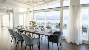 Ein Esszimmer mit großem Tisch, gedeckt für sechs Personen, großen Fenstern mit Bergblick und einer Kristallleuchter.